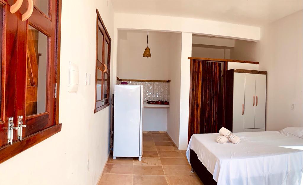 Habitación doble luminosa con cortinas blancas y ventana de madera